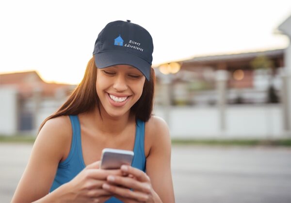 Bitney Adventures Organic Baseball Cap With Logo - Girl on Cell Phone Outside Wearing Cap - Pacific